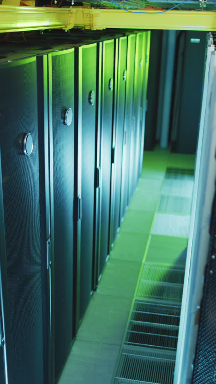 toma un primer plano vertical de los servidores en una sala de servidores cubierta de luz verde