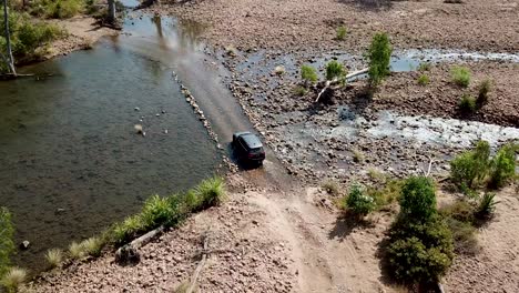 Vista-Aérea-De-Un-Vehículo-Todoterreno-Vadeando-Un-Río-En-El-Interior-De-Australia