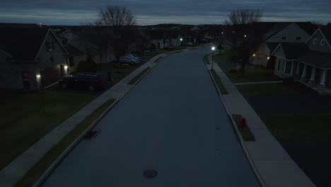 Vuelo-Aéreo-Sobre-La-Calle-Oscura-En-La-Noche-En-El-Barrio-Residencial-Americano-Iluminado-Por-Las-Luces-De-La-Calle