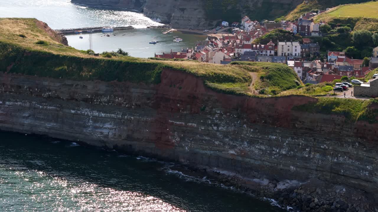 Veduta aerea con drone del porto di Staithes sulla costa del North Yorkshire con fiume, case e barche in una soleggiata mattina di agosto, in estate.