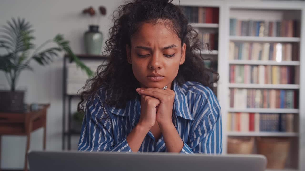 Pensive young indian woman with laptop thinking of creative ideas at home office