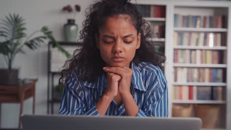 pensive young indian woman with laptop thinking of creative ideas at home office