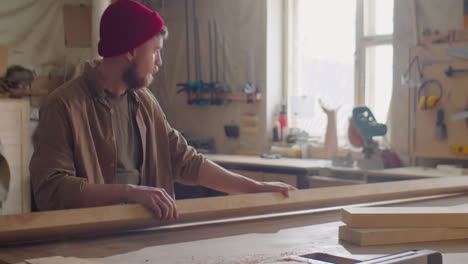 woodworker putting plank on workbench