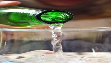 closeup of pouring water from a green bottle into a glass