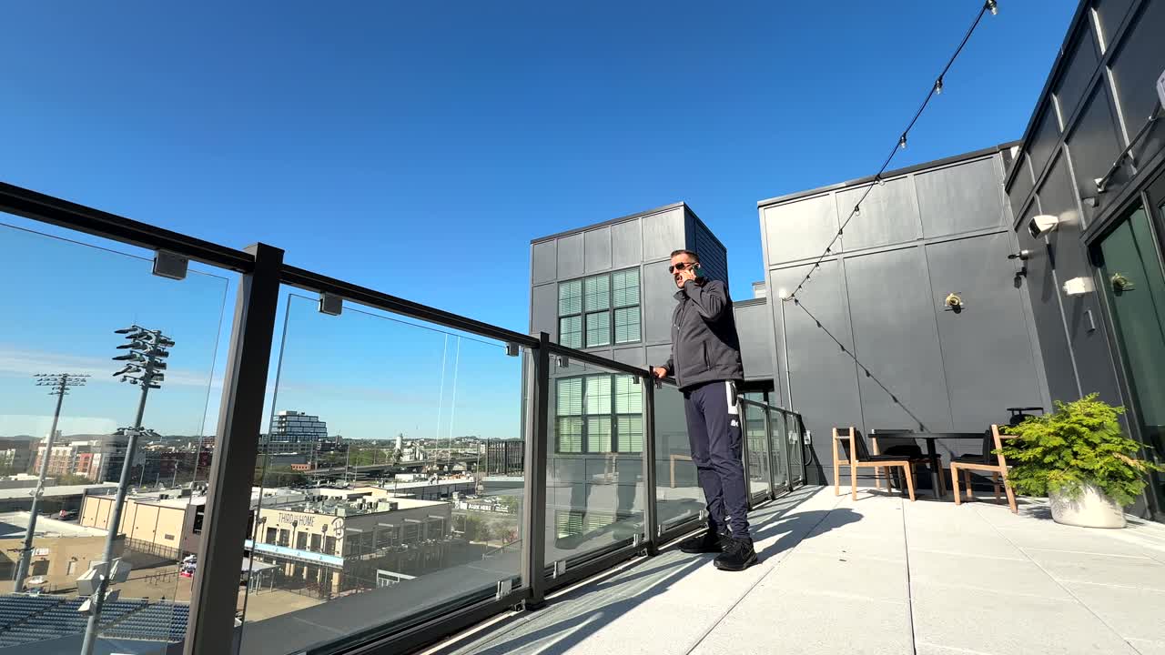 Man takes an upsetting phone call while standing on an outdoor balcony, visibly stressed and emotional, the tension and disappointment of a difficult conversation