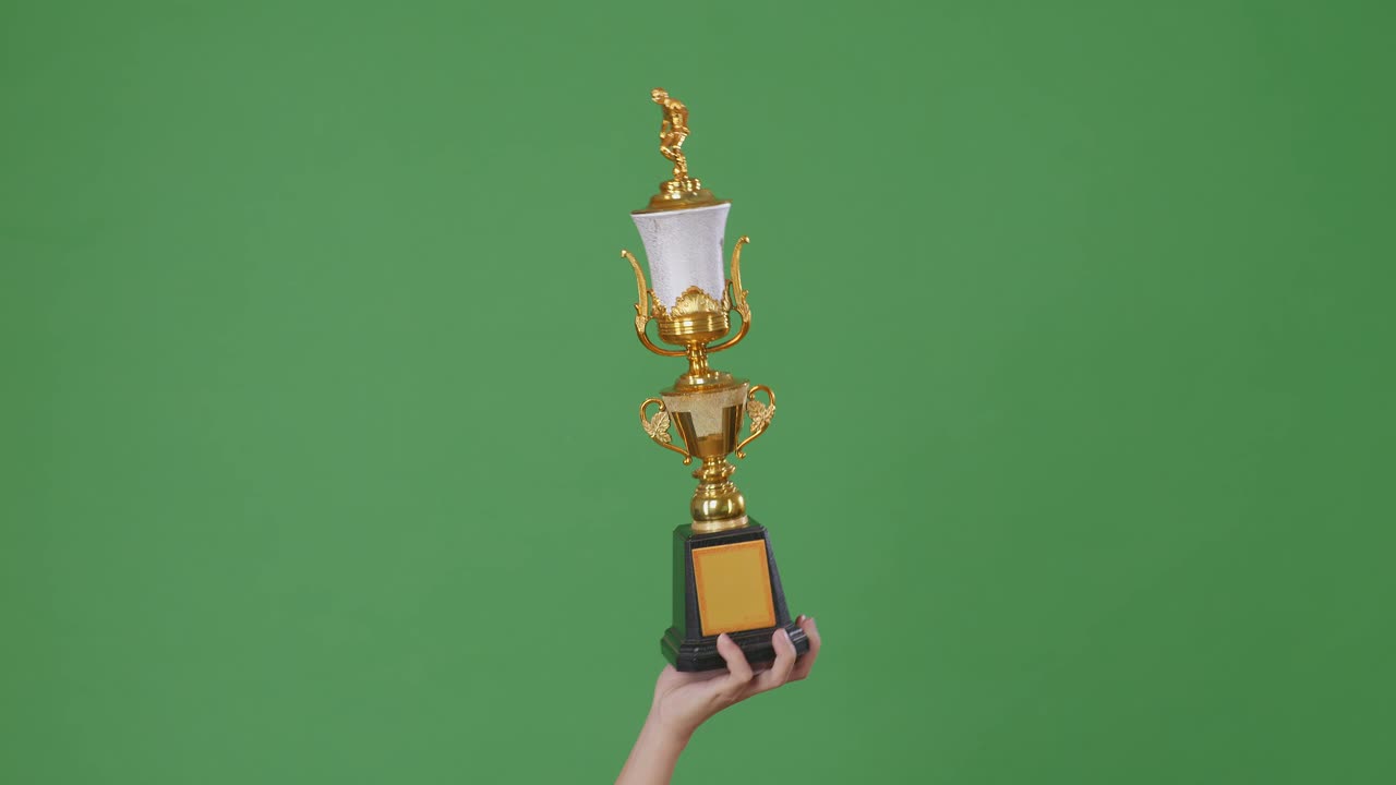 mano sosteniendo un trofeo de oro contra una pantalla verde