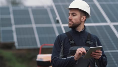 porträt eines arbeiters in einem helm mit einem tablet auf dem hintergrund eines solarkraftwerks