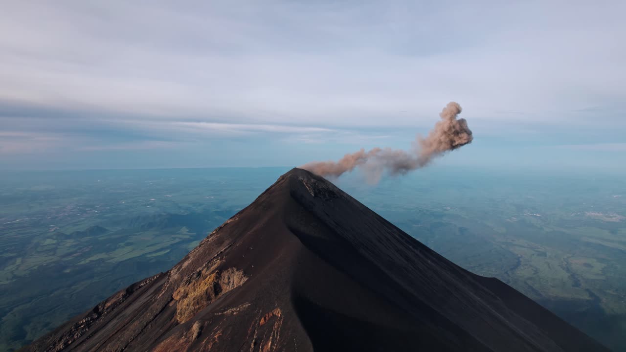 A breathtaking drone shot captures the active Volcán de Fuego in Guatemala, with a plume of ash and gas rising from its summit