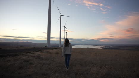 model walking below windmills at sunset in slow-motion