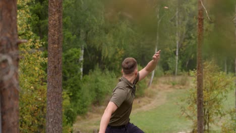 Disc-golfer-throws-a-backhand-throw-from-elevated-tee---medium-shot