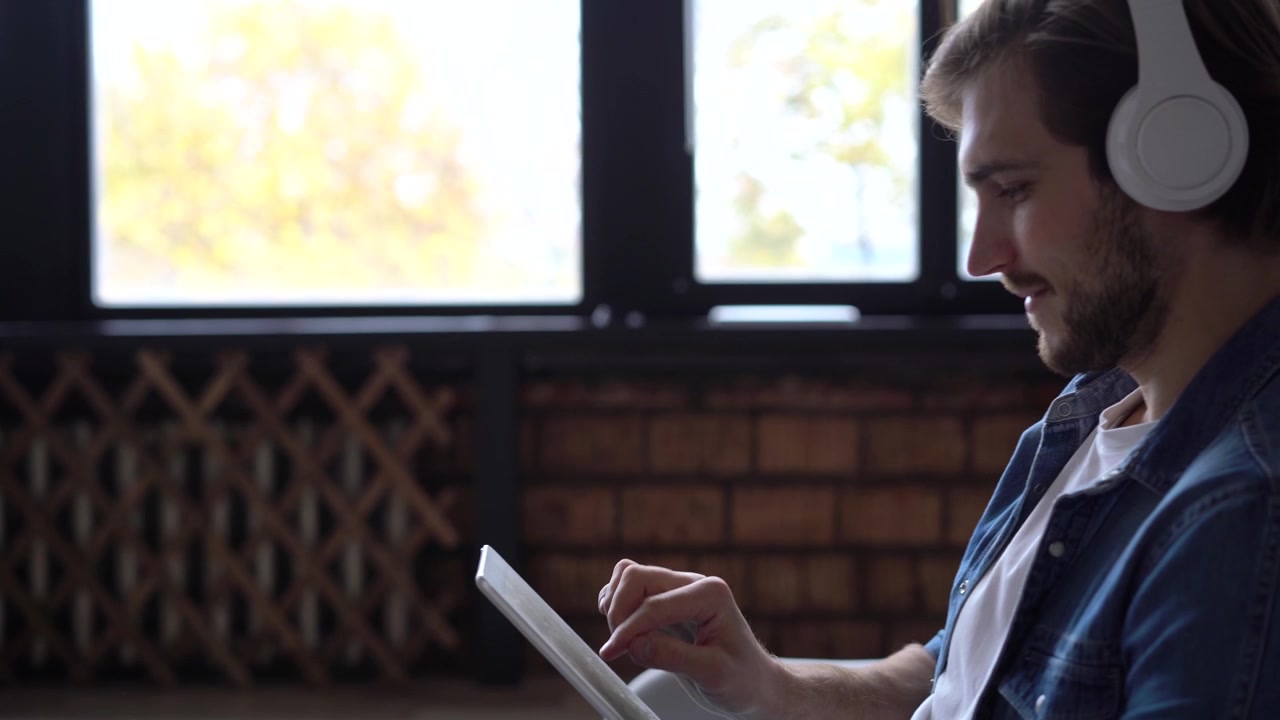 Young Man Using Tablet Computer While Wearing Headphones