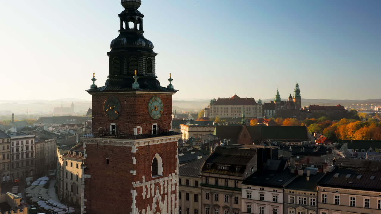 Panorama of Old Town in Krakow, Poland. View on clock on the town hall tower, the Wawel castle, Grodzka street and tenement houses with autumn colors at morning