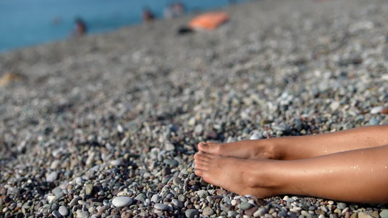 Piedi di donna su una spiaggia di ciottoli