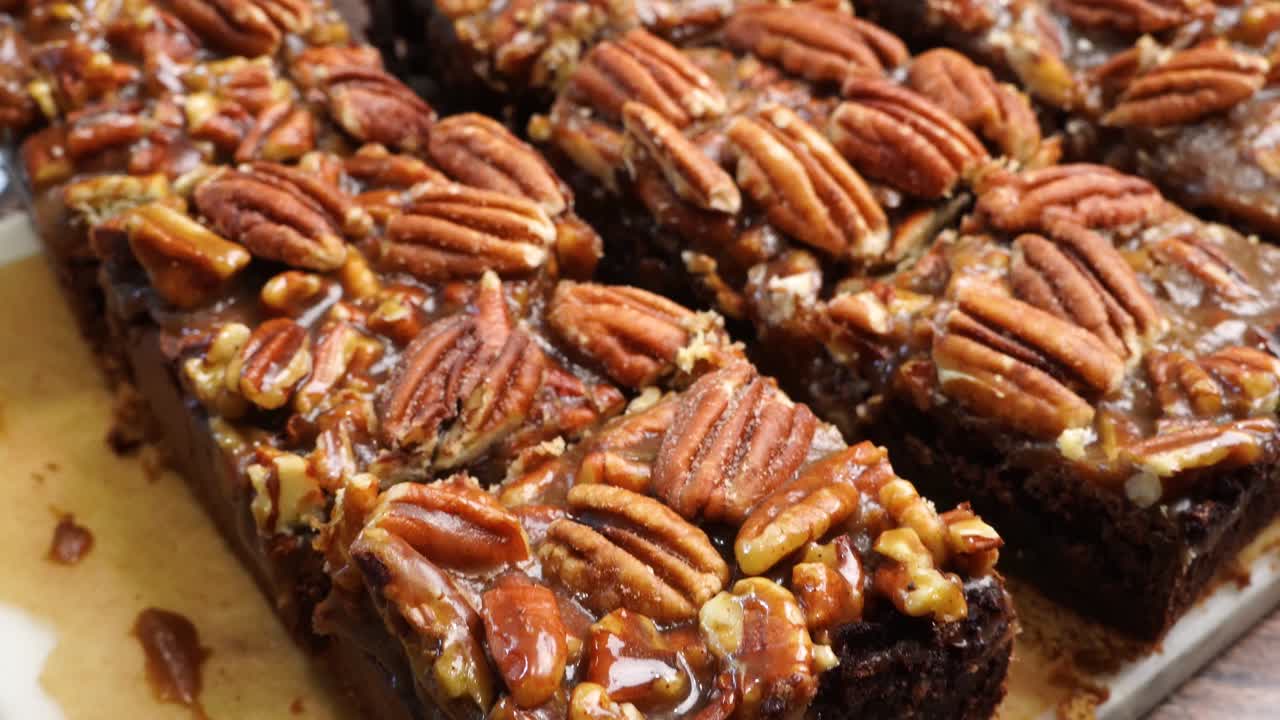 Baking delicious caramel pecan brownies. Close up filming of caramel pecan brownies. Freshly baked gooey chocolate brownies with sweet caramel and nutty pecans.