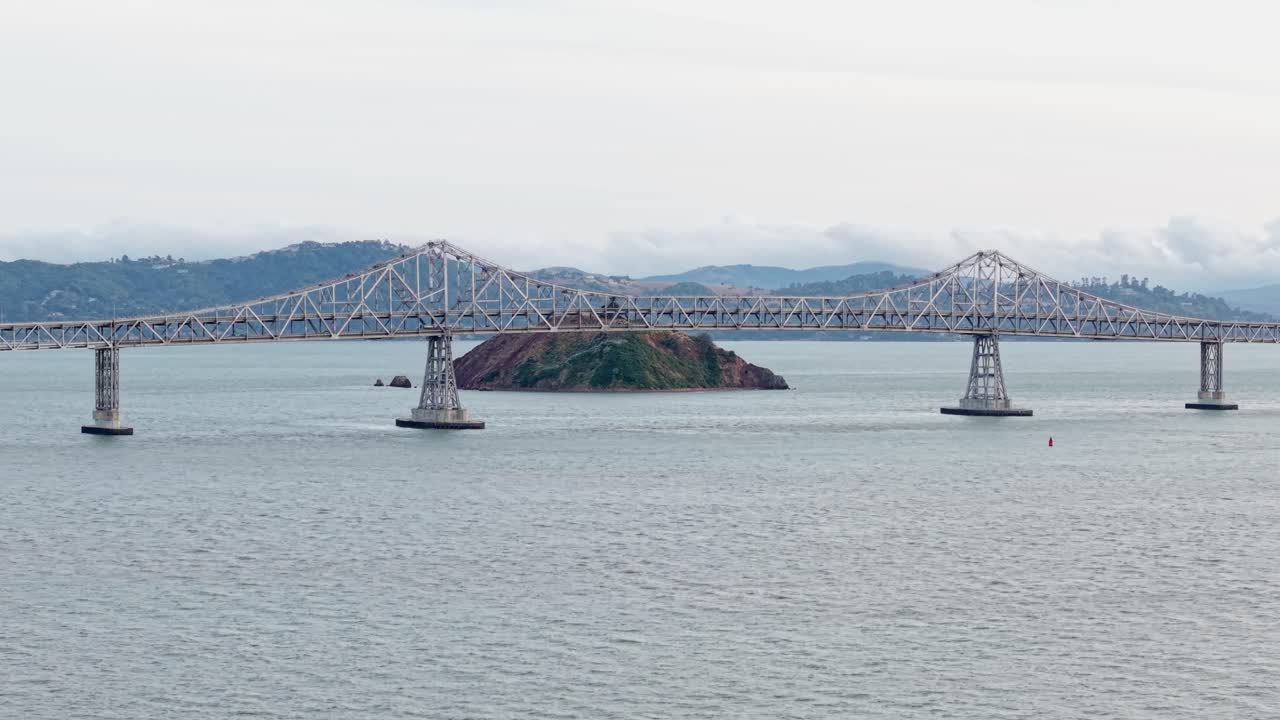The long structure of the bridge extends from city to city, cutting across still water in a quiet display of engineering and movement.