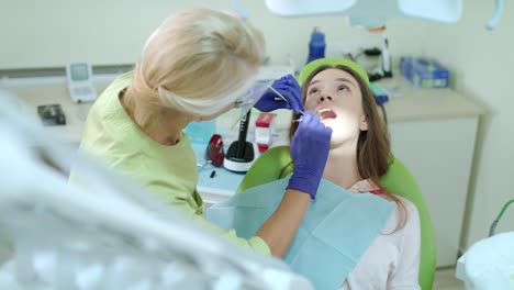 dentista con guantes médicos examinando los dientes del paciente. paciente femenina curando los dientes
