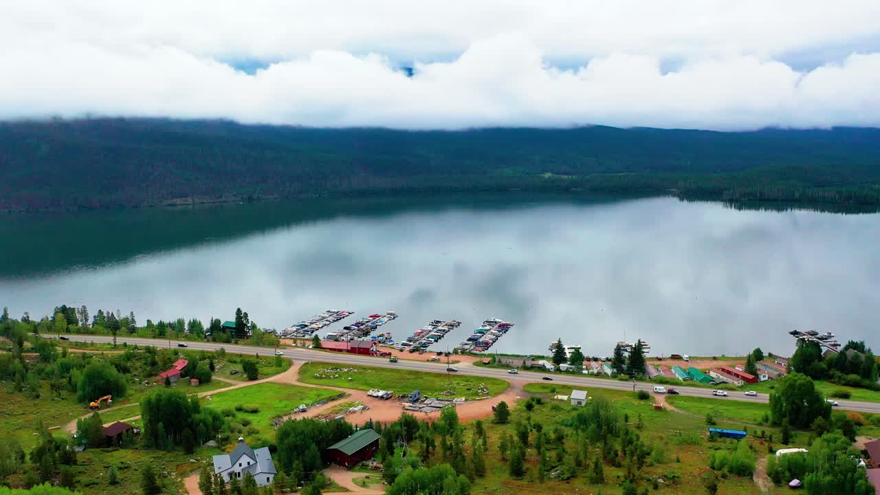 coches conduciendo por la impresionante costa del lago de montaña con rodamientos en el fondo y vidrio calma agua reflectante