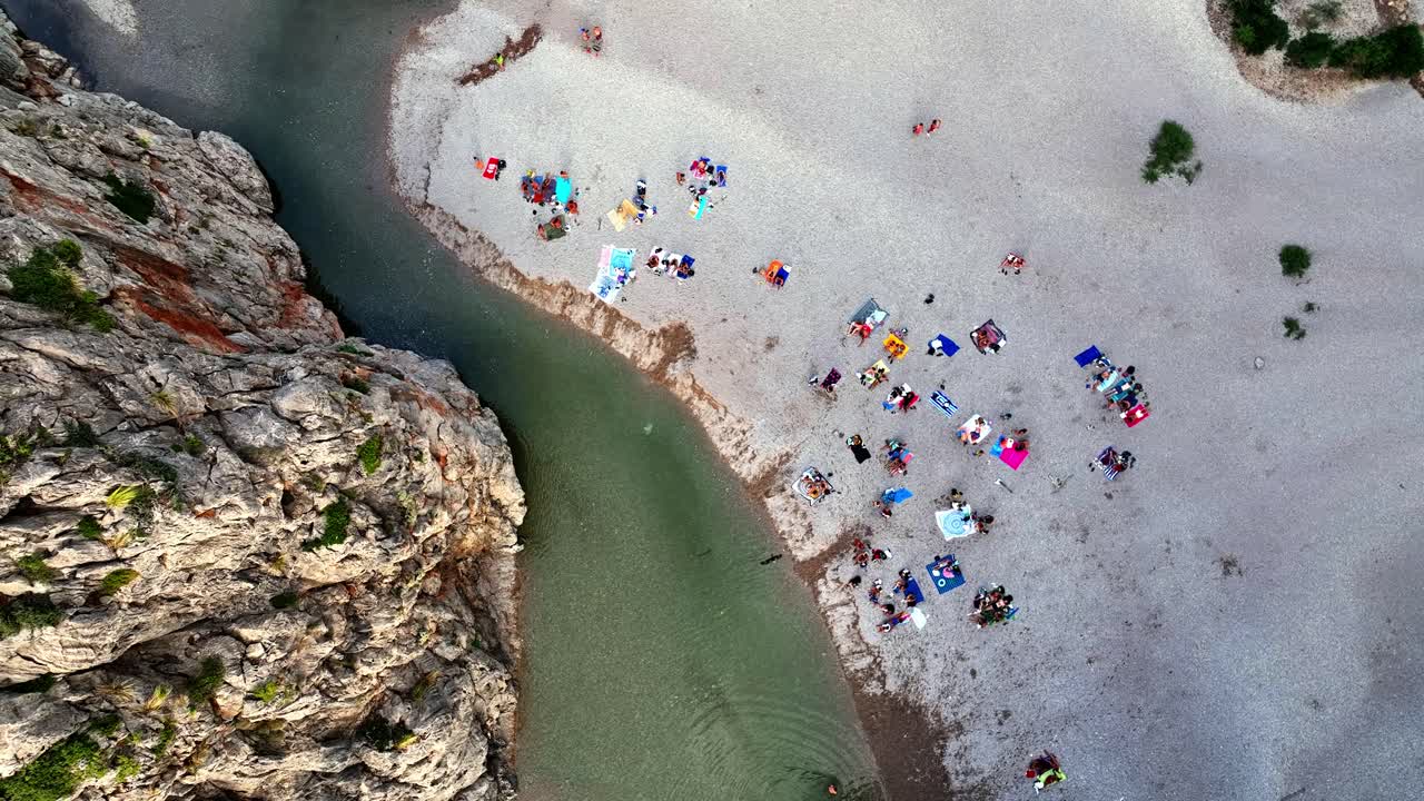 Drone shot rising and filming down on a beach by a mountain.