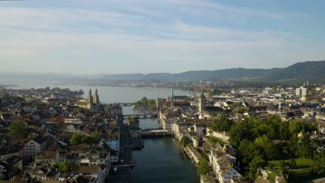 Ascending-Shot-Above-Zurich's-Old-Town---Grossmünster,-Church-of-St-Peter,-Fraümunster,-Lake-Zurich