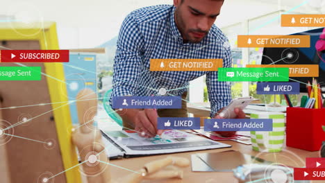 working at desk, man using smartphone with social media notifications animation over
