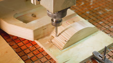 máquina cnc dinámica de perforación en madera contrachapada, asegurada por pinzas en una mesa a cuadros