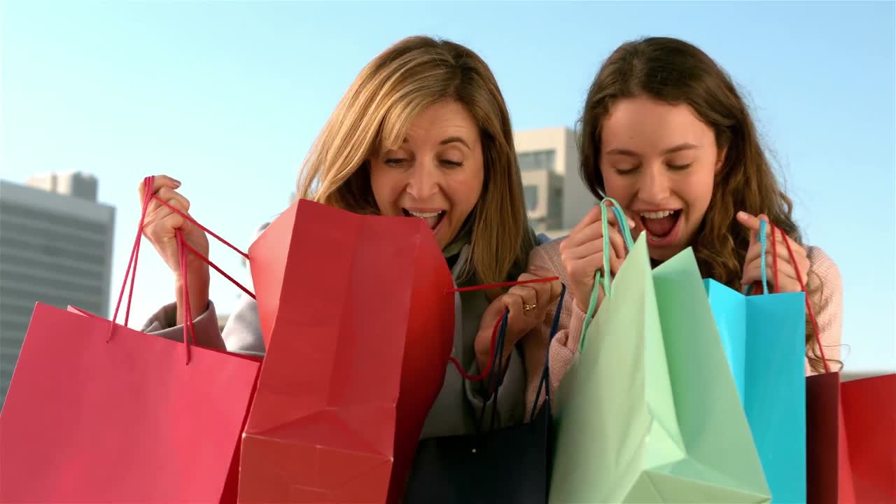 madre e hija mirando en sus bolsas de compras