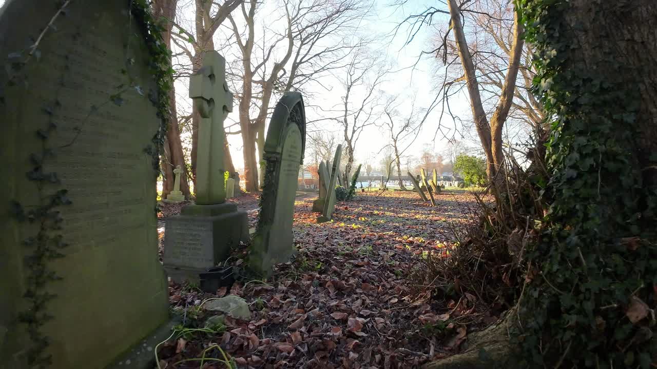 fpv volando alrededor de lápidas en el cementerio nevado del cementerio del amanecer del otoño durante la brillante hora dorada