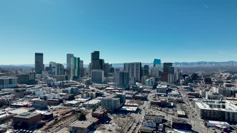 Drone-shot-of-downtown-Denver,-Colorado-on-a-sunny-day-with-urban-developments-as-far-as-the-eye-can-see