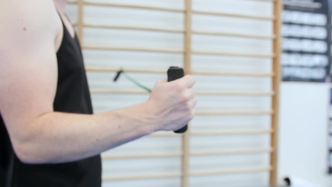 atleta masculino realizando ejercicio de rehabilitación de hombro con banda elástica