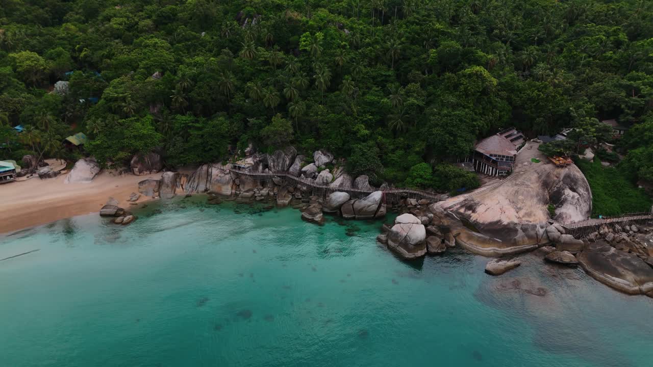 Aerial footage of a rocky beach, lush jungle, and turquoise sea in Thailand. Tropical coastline with scenic rocks, forest, and clear water. Perfect for travel, tourism, nature, and adventure projects.