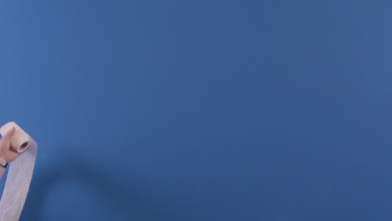 se ve una mano tirando un rollo de papel higiénico a la cámara