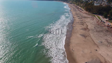 broken sea pier with shipwreck on the california coastline, aerial view