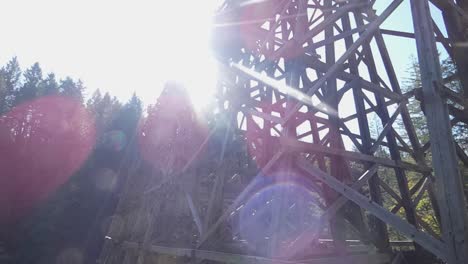 Slow-moving-camera-shot-of-train-trestle-and-light-flares-in-forest