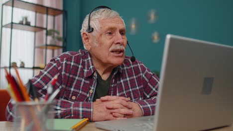 senior man freelance wear headphone make video call talking teaching at laptop at home office