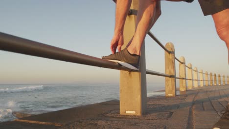 hombre mayor atando sus cordones de zapatos en el paseo marítimo