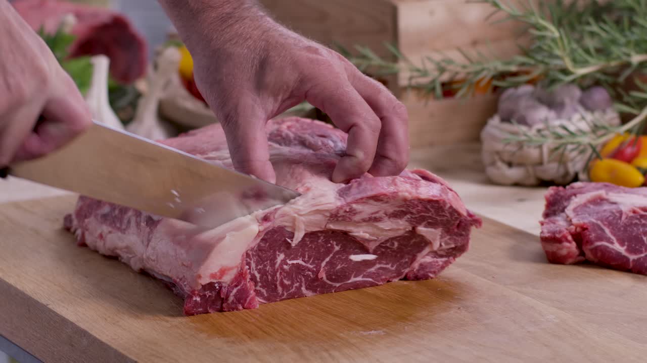 Close up seorang chef ahli mengukir steak ribeye marmer tebal dan mewah dari daging sapi panggang berkualitas tinggi di dapur rumah steak mewah