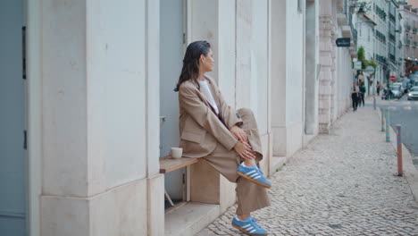 chic girl relaxing street alone looking on road. carefree woman sitting bench