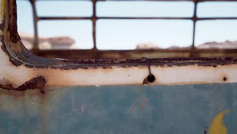 Rust-window-detail-of-an-abandoned-bus-in-Atacama-desert,-South-America,-Chile