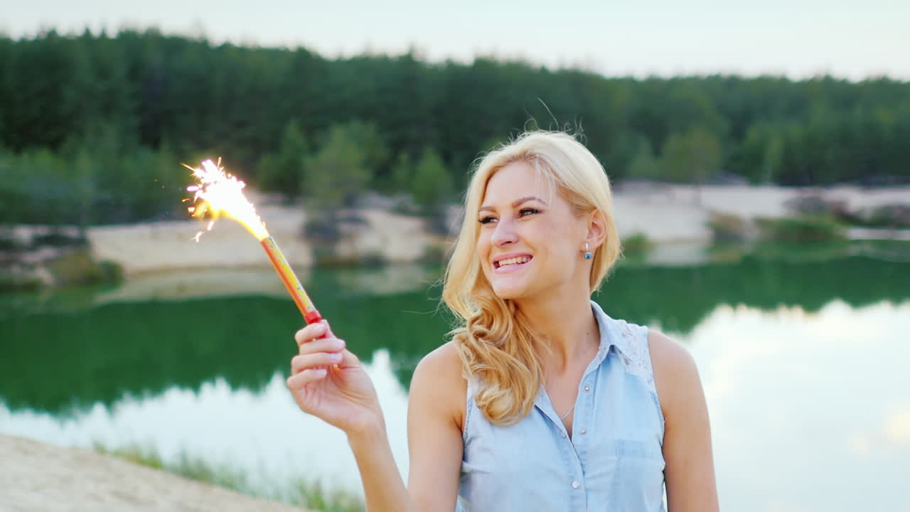 привлекательная блондинка с фейерверком и искрой в руке, чтобы повеселиться