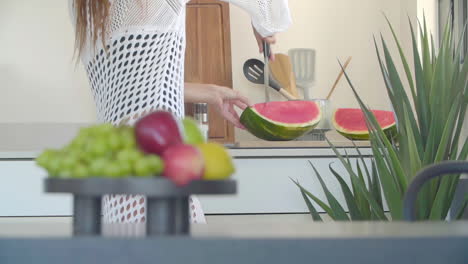 half body view of a woman cutting fresh watermelon in the kitchen