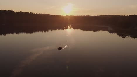 person paddling boat across the calm lake on a sunset in poland