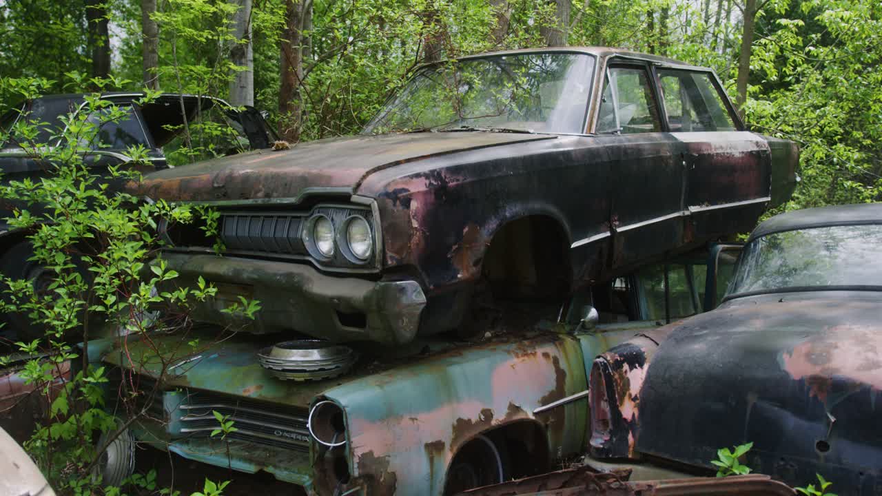 старинные американские машины 1970-х годов, сложенные друг на друга, ждут сброса.