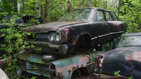 vintage american built cars from the 1970s stacked on top of each other waiting to be scrapped