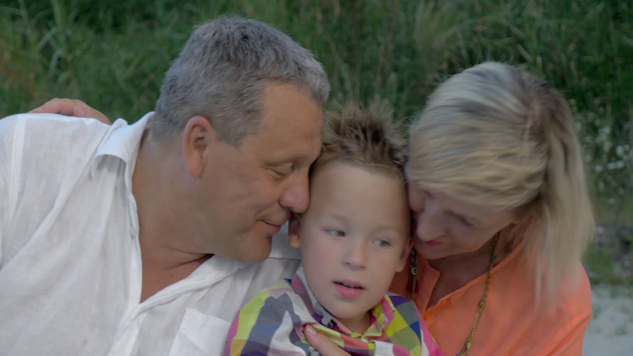 할아버지와 할머니가 손자를 포옹하고 키스하고 있습니다.