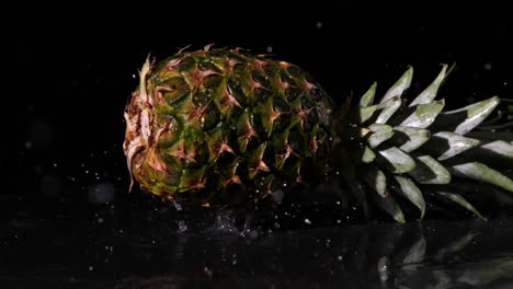 piña cayendo sobre una superficie negra y húmeda