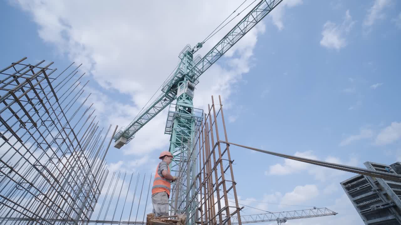 un trabajador utiliza alambre de ataduras de acero para sujetar barras de acero a barras de refuerzo. estructuras de hormigón armado - tejer una jaula de reforzo de metal.