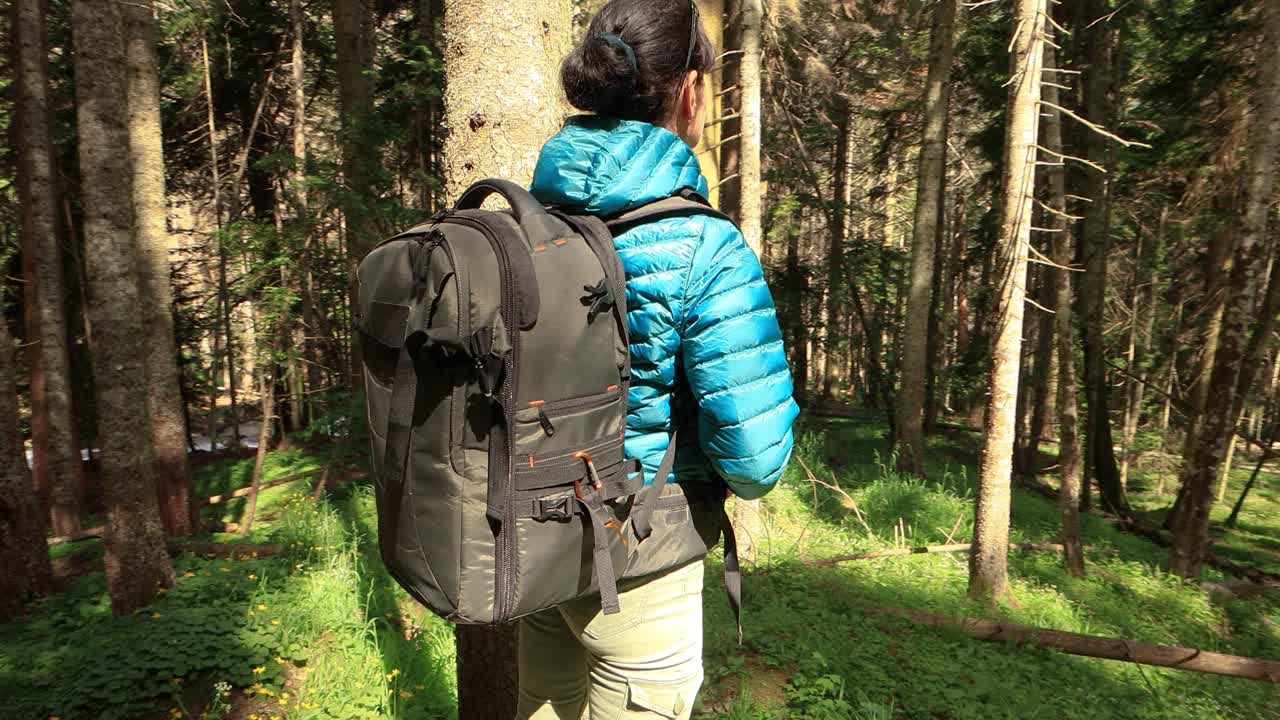 Hiking woman walk with a hiking backpack in spring green forest