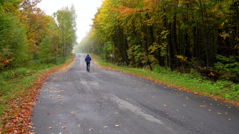 Hombre-Corriendo-En-Una-Pequeña-Carretera-Rodeada-De-Arce-Otoño-Hoja-De-Arce