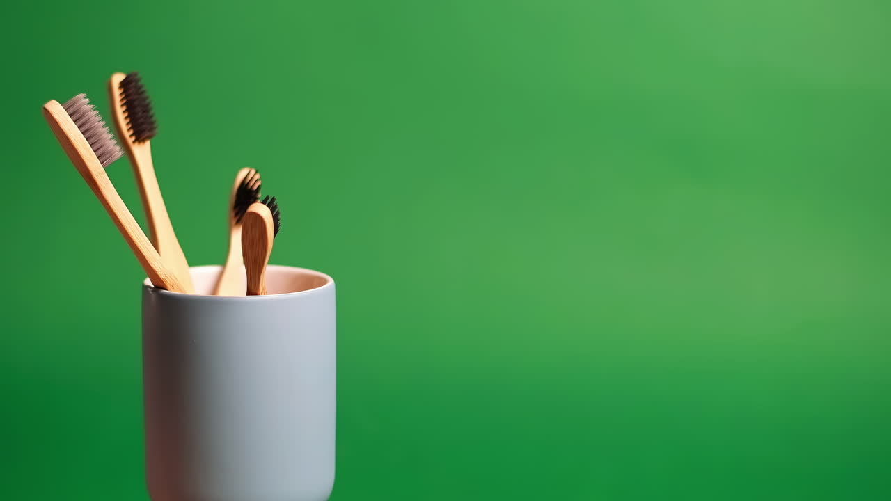 Bamboo toothbrush in a glass demonstrating with a green background