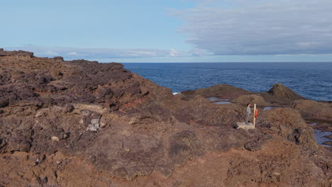 woman on volcanic rocks near punta sardina lighthouse, gran canaria, canary islands, spain